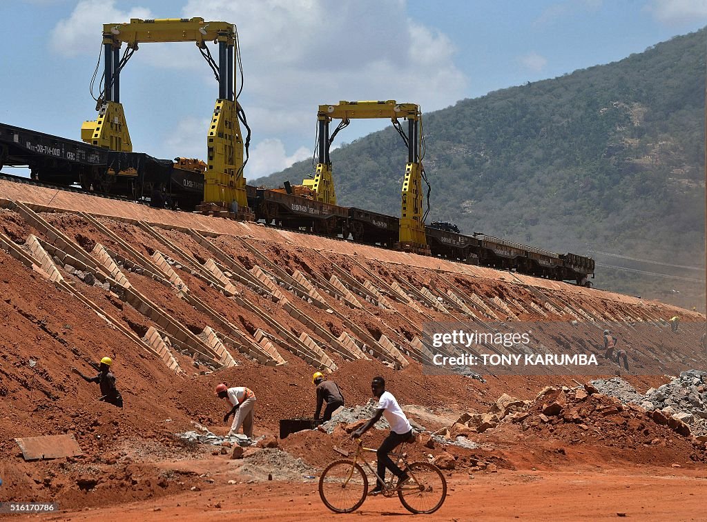 man-cycles-past-labourers-working-on-the-construction-of-a-section-of-picture-id516170786