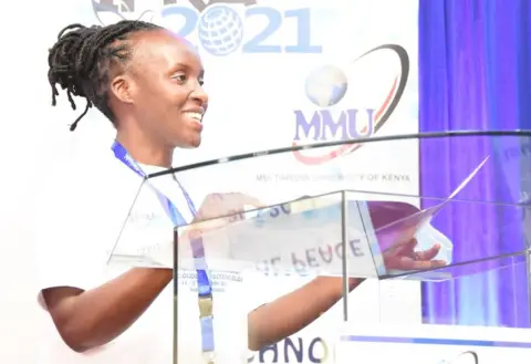 Multimedia University Dr Gladys Nyachieo standing at a lectern at a Multimedia University event.