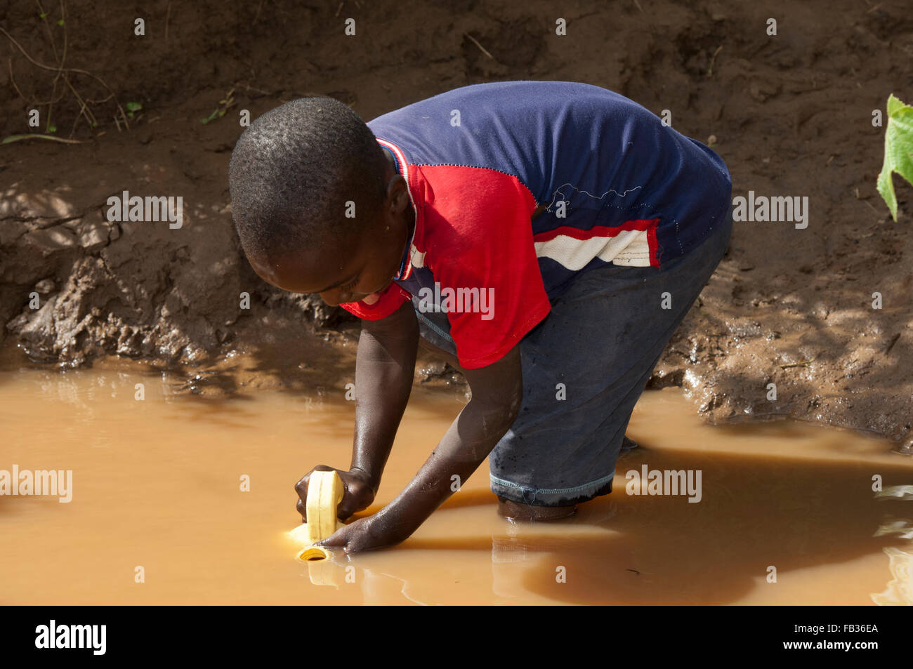 young-child-getting-water-from-a-muddy-river-kenya-FB36EA.jpg