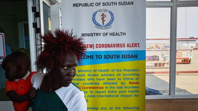 A passenger walks past a coronavirus health sign in South Sudan