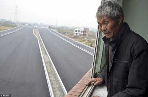 Luo-Baogen-looks-out-on-the-new-road-which-is-yet-to-be-officially-opened-from-the-apartment-building-where-all-his-neighbours-moved-out.jpg