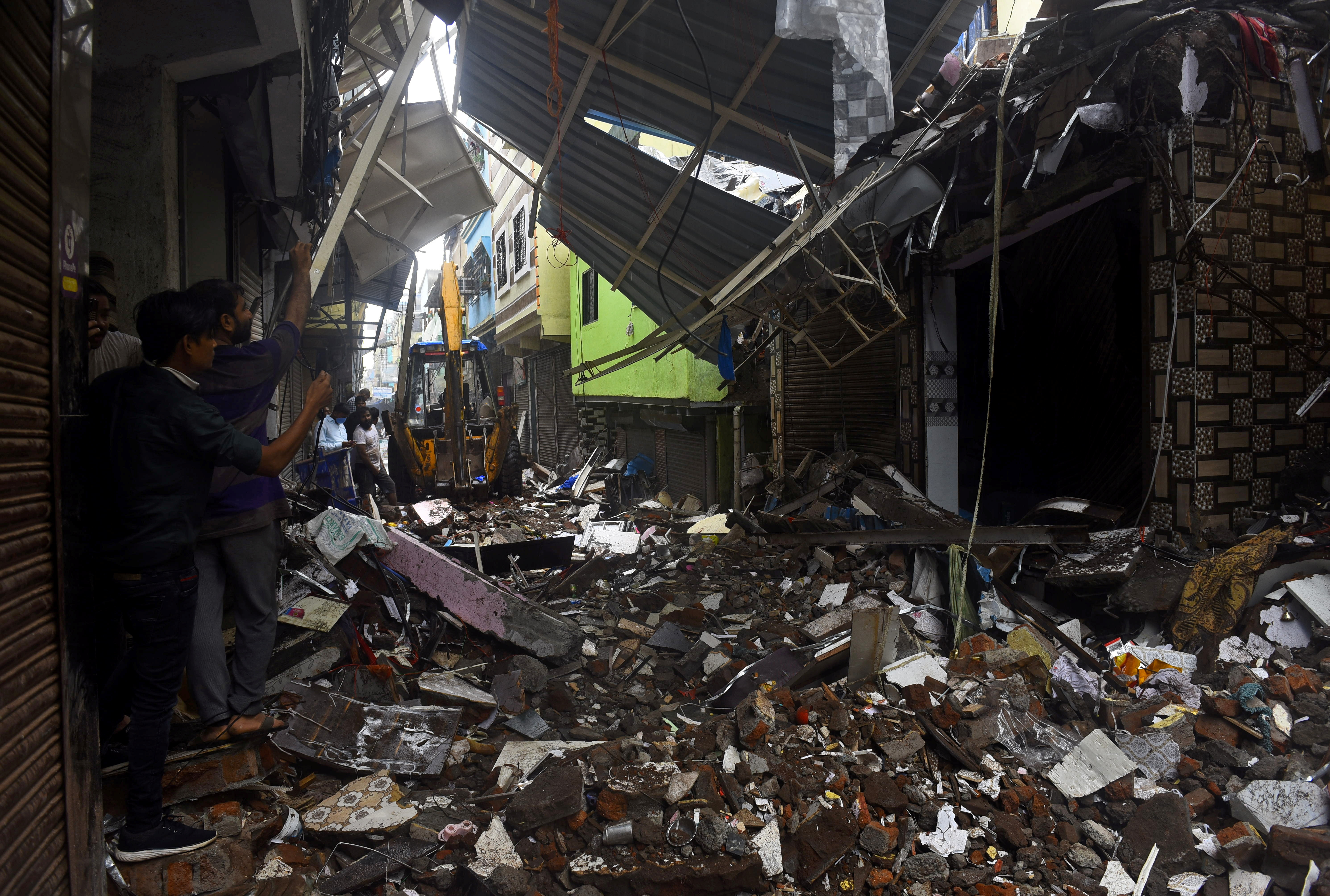 People use their mobile phones to take pictures of a collapsed building following rains in Mumbai, India, July 23, 2021. REUTERS/Stringer