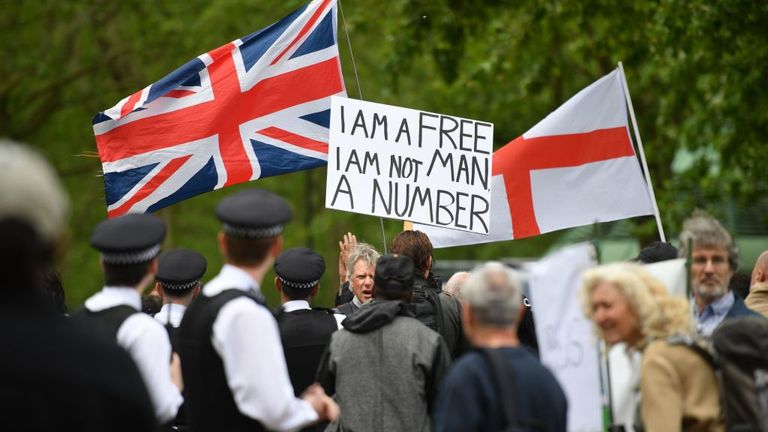 Police attend an anti-coronavirus lockdown demonstration with protesters holding a Union Flag (L), a Flag of St George (R) and a placard that reads I am a free man, I am not a number in Hyde Park in London on May 16, 2020, following an easing of lockdown rules in England during the novel coronavirus COVID-19 pandemic. - Fliers advertising 'mass gatherings' organised by the UK Freedom Movement to oppose the government lockdown measures and guidelines put in place to halt the spread of coronavir