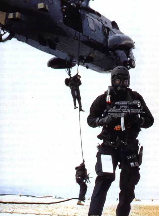 SBS MARINES abseiling from helicopter holding MP5 A3 9mm submachine guns helmets wet suits gas masks goggles