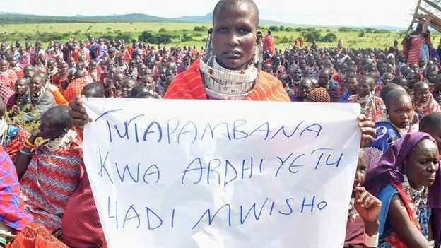 _97406776_a_maasai_woman_holds_a_sign_that_reads_in_swahili_%27we_will_fight_for_our_land_until_the_end%27.jpg
