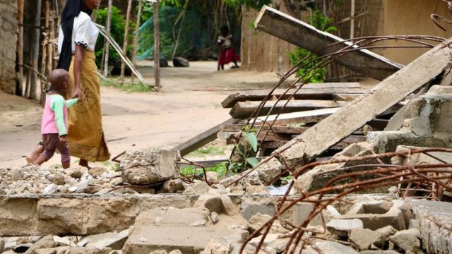 Wakazi wa Nanduadua wakipita katika eneo lenye mabaki ya msikiti unaodaiwa kuharibiwa na vikosi vya kijeshi vya Msumbiji