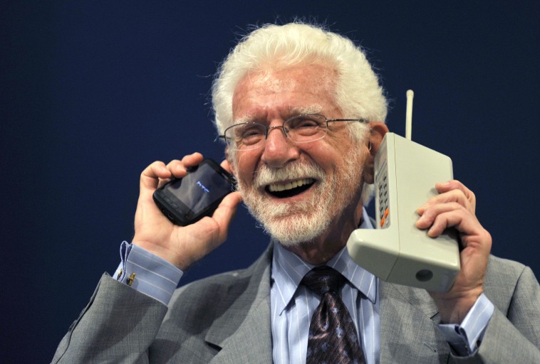 Bwana Martin Cooper akishikilia Motorola DynaTAC kushoto kwake na simu yake nyingine aliyokuwa anatumia, picha hii ni ya mwaka 2009.