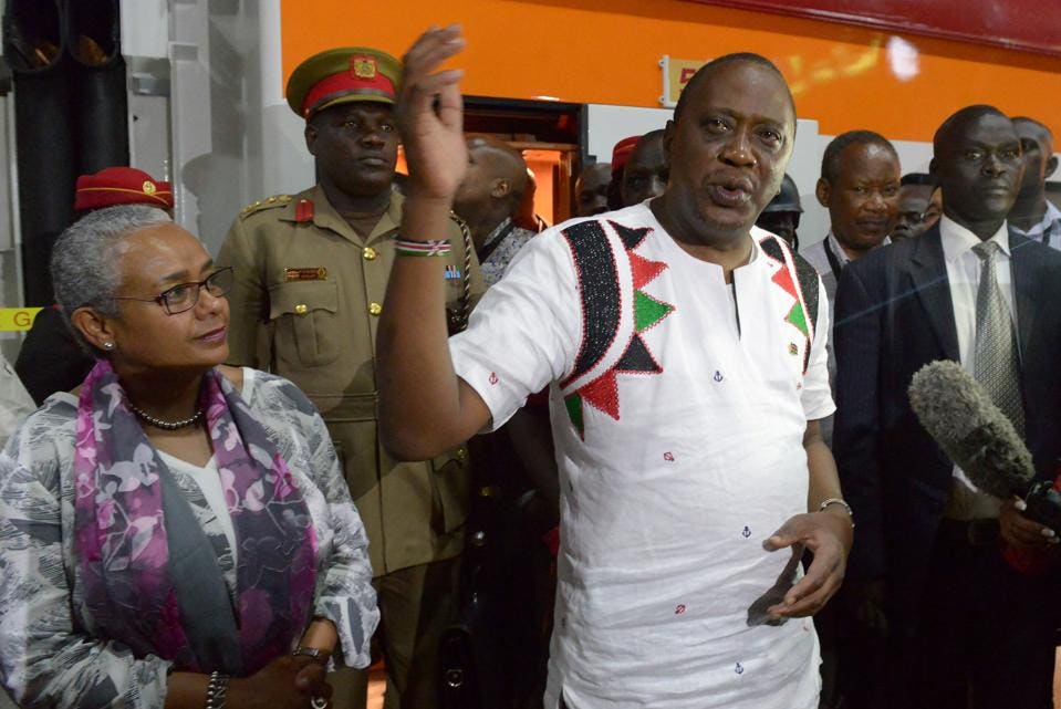 Kenya's President Uhuru Kenyatta, flanked by First Lady Margaret Kenyatta (L), addresses medias upon after arriving on a train from Mombasa, on May 31, 2017 in Nairobi. More than a century after a colonial railway gave birth to modern Kenya, the country is betting on a new Chinese-built route to cement its position as the gateway to East Africa. The $3.2 billion (2.8 billion euro) railway linking Nairobi with the port city of Mombasa will Wednesday take its first passengers on the 472 kilometre (293 mile) journey, allowing them to skip a hair-raising drive on one of Kenya's most dangerous highways. / AFP PHOTO / SIMON MAINA (Photo credit should read SIMON MAINA/AFP/Getty Images)