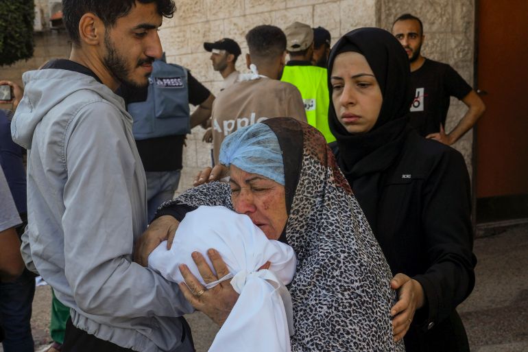 A Palestinian woman kisses the sheet-covered body of a child killed during an Israeli airstrike